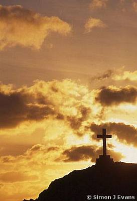 Silhouette of stone cross against sun - Llanddwyn Island